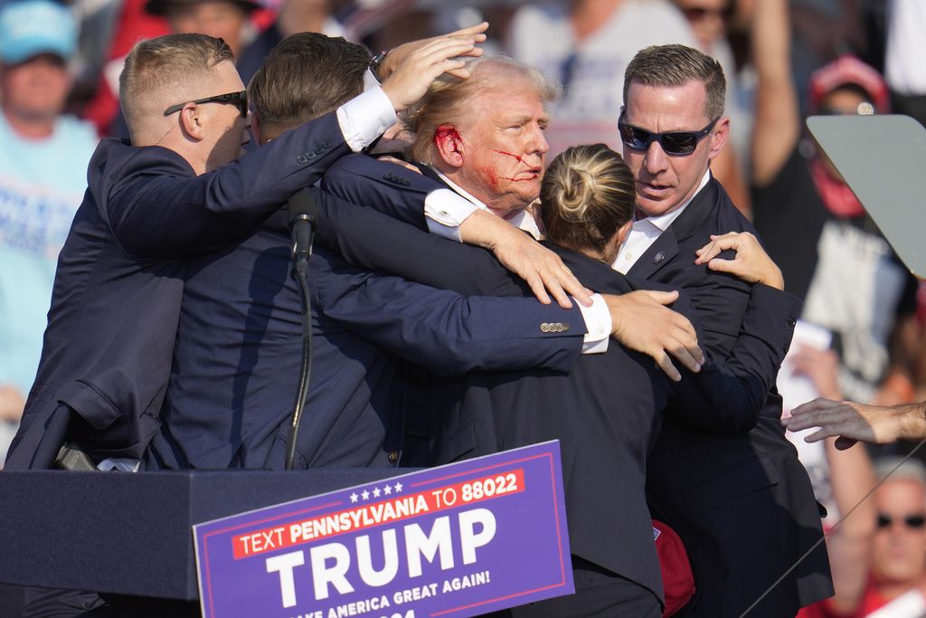 Kandidat presiden dari Partai Republik, mantan Presiden Donald Trump, dibantu turun dari panggung pada acara kampanye di Butler, Pennsylvania, Sabtu (13/7/2024). 