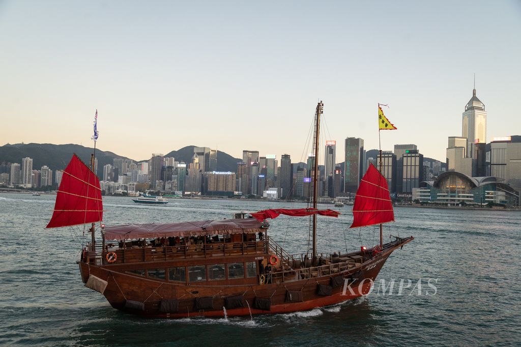 Kapal tradisional <i>junk boat </i>membawa wisatawan mengarungi selat sempit yang memisahkan Pulau Hong Kong dan Semenanjung Kowloon, Selasa (21/11/2023).