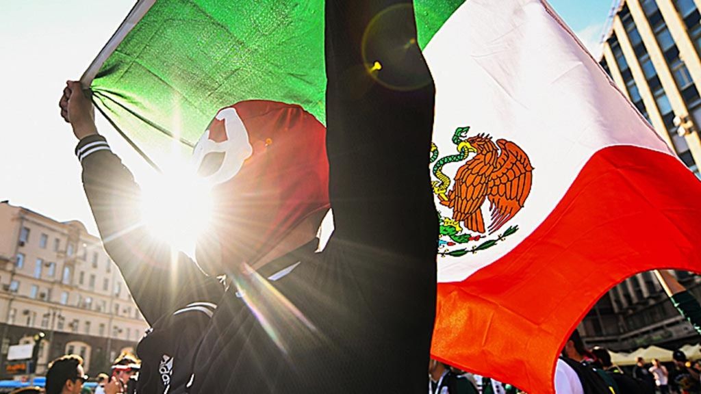 Pendukung Meksiko yang mengenakan topeng membentangkan bendera, merayakan keberhasilan Meksiko, Amerika Serikat, dan Kanada yang terpilih menjadi tuan rumah bersama untuk Piala Dunia 2026. Pemilihan tuan rumah Piala Dunia 2026 itu diputuskan FIFA pada 13 Juni 2018 di Moskwa, Rusia.