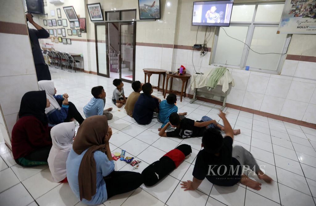 Anak-anak penghuni Panti Asuhan Kampung Melayu, Jakarta memanfaatkan waktu libur dengan menonton televisi bersama-sama, Minggu (30/10/2022).