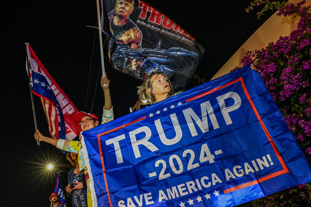 Arsip foto pada 15 November 2022 memperlihatkan pendukung mantan Presiden AS Donald Trump membentangkan spanduk di luar kediaman Trump di Mar-A-Lago, West Palm Beach, Florida. Trump memulai kampanye untuk maju sebagai calon presiden AS dalam pemilu 2024 mendatang. 