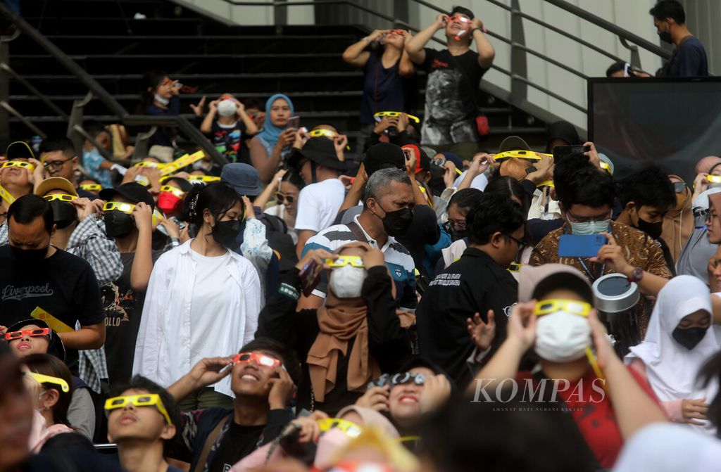 Warga mengamati fenomena gerhana matahari parsial di Plaza teater Kecil Taman Ismail Marzuki, Jakarta (20/4/2023). Masyarakat menyaksikan gerhana Matahari parsial tersebut, baik dengan bantuan alat teleskop maupun kacamata gerhana. 