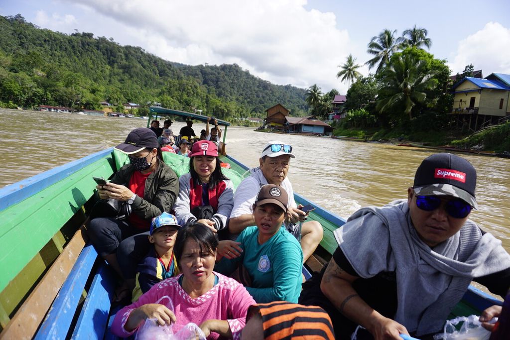 Penumpang perahu kayu duduk berjejalan tanpa atap saat bepergian jauh melintasi Sungai Mahakam di Kecamatan Long Pahangai, Mahakam Ulu, Kaltim, Senin (9/12/2019).