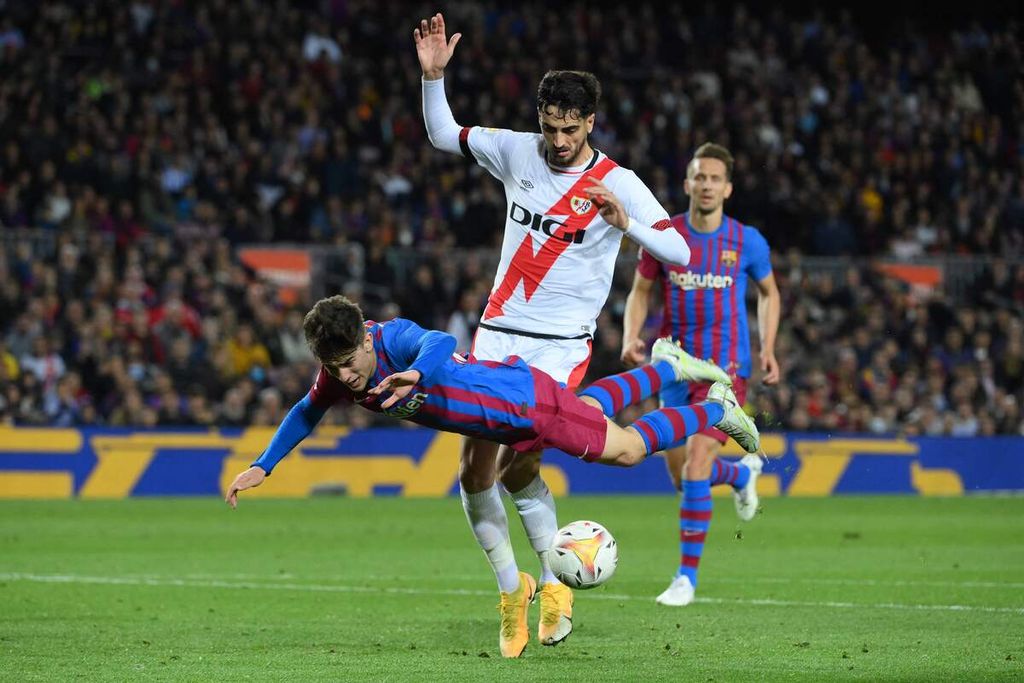 Pemain Barcelona, Gavi, terjatuh saat berebut bola dengan pemain Rayo Vallecano, Alejandro Catena, pada laga Liga Spanyol di Stadion Camp Nou, Senin (25/4/2022) dini hari WIB. Rayo Vallecano menang dengan skor 1-0. 