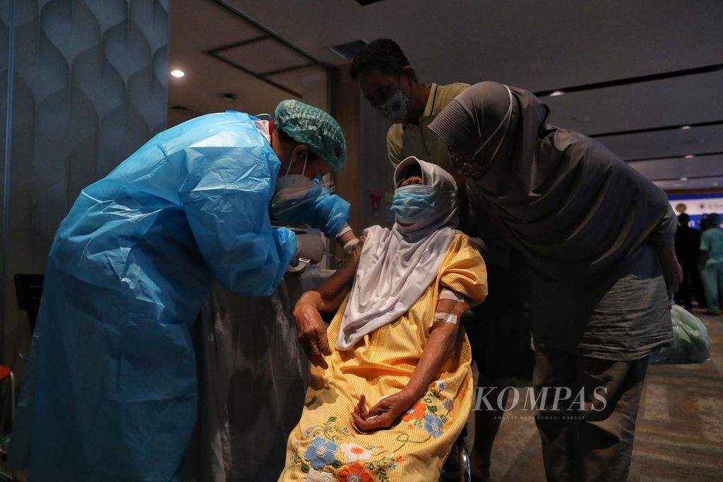 Rukiah (84) menerima vaksin AstraZeneca saat peresmian Sentra Vaksinasi Tiket.com di Rumah Sakit St Carolus, Jakarta, pertengahan Juni 2021. Warga lansia kini boleh mendapatkan vaksinasi penguat atau <i>booster </i>kedua. 