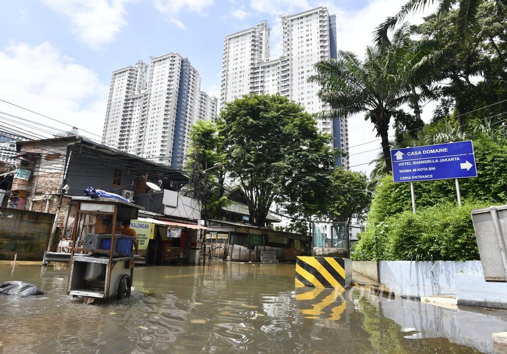 Penjual makanan mendorong gerobak melewati banjir di Jalan Karet Pasar Baru Timur, Tanah Abang, Jakarta Pusat, Minggu (23/02/2020). Sejumlah kawasan di Jakarta kembali dilanda banjir setelah hujan deras mengguyur Jakarta sejak Sabtu malam hingga Minggu Pagi. 