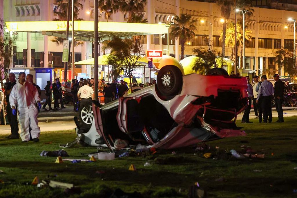 Polisi Israel berkumpul di dekat sebuah mobil terbalik yang digunakan dalam serangan di Tel Aviv, Jumat (7/4/2023). 