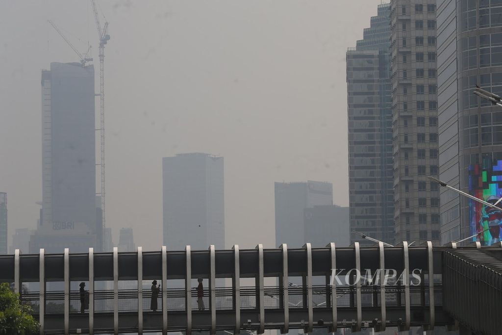 Warga melalui jembatan penyeberangan orang dengan latar belakang gedung-gedung bertingkat yang diselimuti asap polusi udara di kawasan Jakarta Selatan, Jumat (8/10/2021). Menurut data AirVisual, situs penyedia peta polusi daring harian kota-kota besar di dunia, pada 8 Oktober 2021 pukul 09.00 WIB, nilai Indeks Kualitas Udara (AQI) Kota Jakarta adalah 155 atau masuk dalam kategori tidak sehat. Adapun kadar PM 2,5 mencapai 66,9 mikrogram per meter kubik atau jauh melampaui ambang batas.