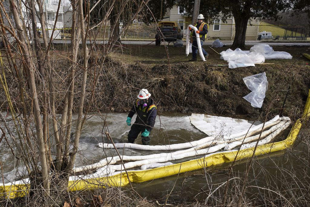 Petugas pengendali dampak pencemaran tengah membersihkan tumpahan bahan kimia dan bahan beracun lain di East Palestine, Ohio pada 9 Februari 2023. Pembersihan itu bagian dari dampak kecelakaan kereta pengangkut bahan kimia dan bahan beracun lainnya pada Jumat (3/2/2023)