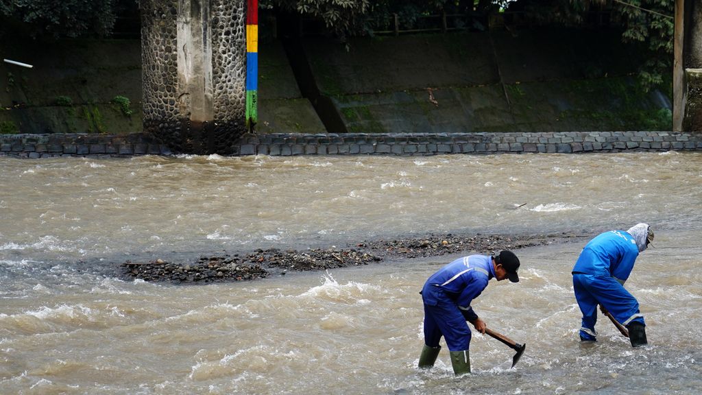 Pekerja melakukan pengerukan material batuan dan pasir di aliran Sungai Ciliwung.