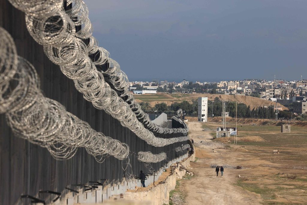 Para pengungsi Palestina berjalan di dekat pagar perbatasan antara Gaza dan Mesir pada 16 Februari 2024 di Rafah. 
