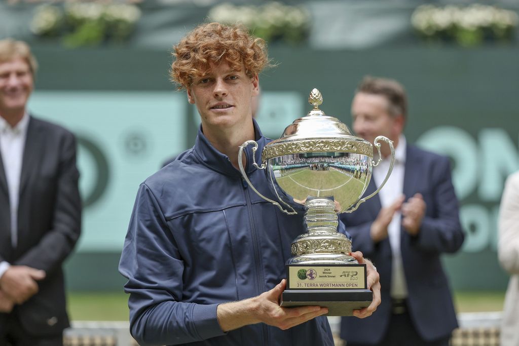 Jannik Sinner memegang trofi juara turnamen tenis ATP 500 Halle seusai mengalahkan Hubert Hurkacz pada final di Halle, Jerman, Minggu (23/6/2024). 