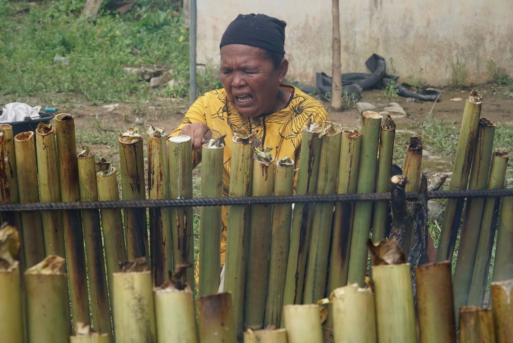 Warga memperbaiki posisi tabung lamang (lemang) agar matang merata dalam acara "Malamang Sakampuang" di Kelurahan Aie Pacah, Kecamatan Koto Tangah, Kota Padang, Sumatera Barat, Sabtu (31/12/2022).