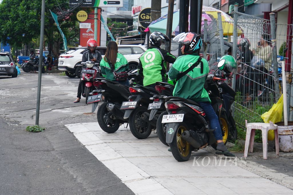 Sopir ojek daring memarkir sepeda motor di tepi Jalan Boulevard Piere Tendean, Manado, Sulawesi Utara, Sabtu (13/5/2023).