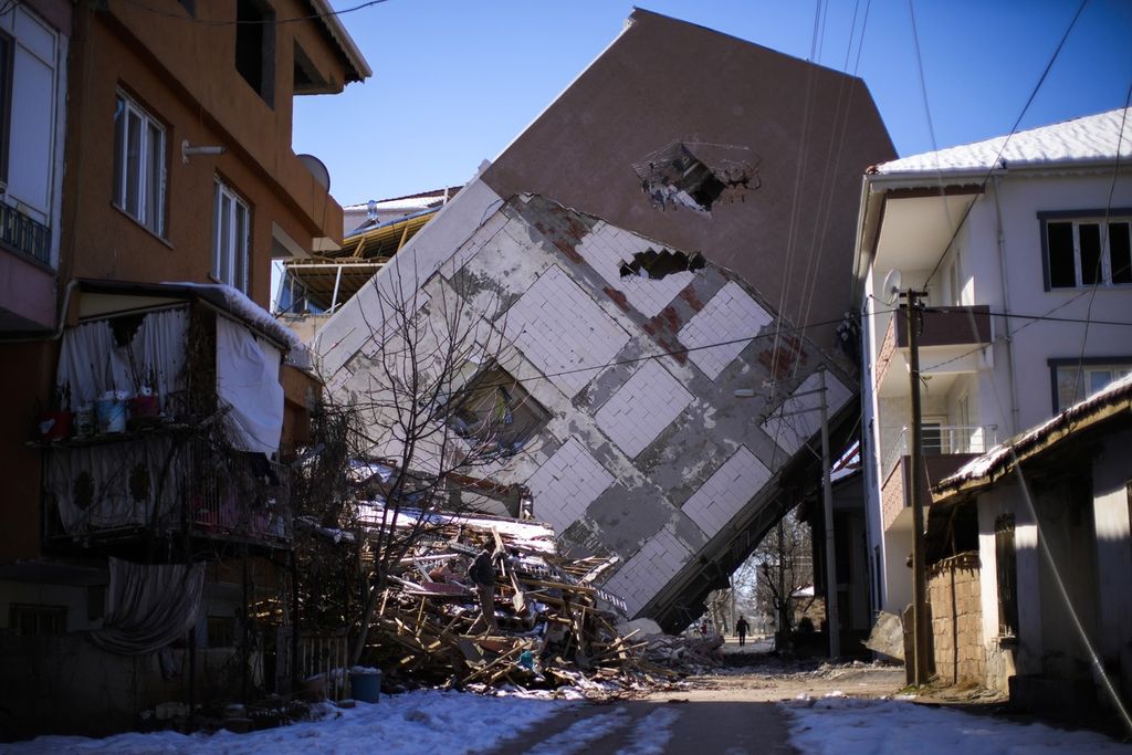  Seorang pria berjalan di dekat sebuah bangunan yang miring setelah diguncang gempa di Golbasi, Turki, Senin (13/2/2023). 