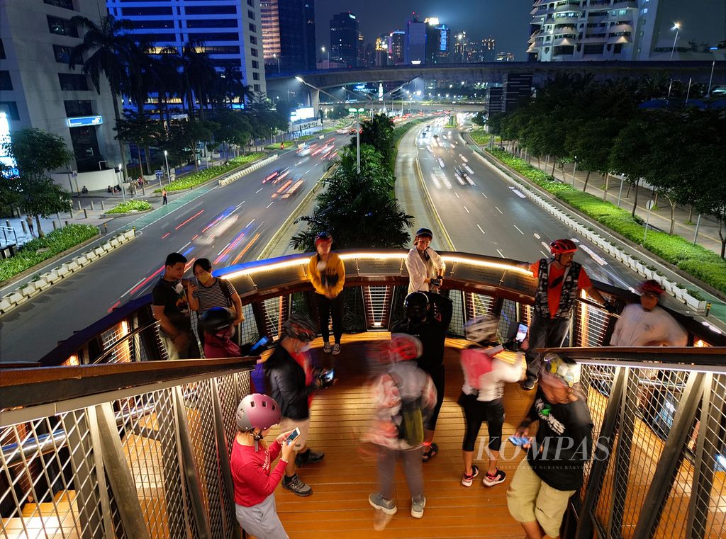 Warga menikmati malam di Jembatan Penyeberangan Orang (JPO) Phinisi di Jalan Sudirman, Jakarta (16/4/2022). JPO yang belum lama diresmikan ini menjadi daya tarik masyarakat untuk sekadar menikmati hari, berfoto, maupun menikmati suasana kota. 