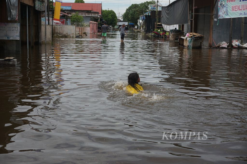 Seorang anak berenang di genangan banjir di depan rumahnya di wilayah Katingan Hilir, Kabupaten Katingan, Kalimantan Tengah, Minggu (13/9/2020). Setidaknya 21 kecamatan di Kalteng direndam banjir.