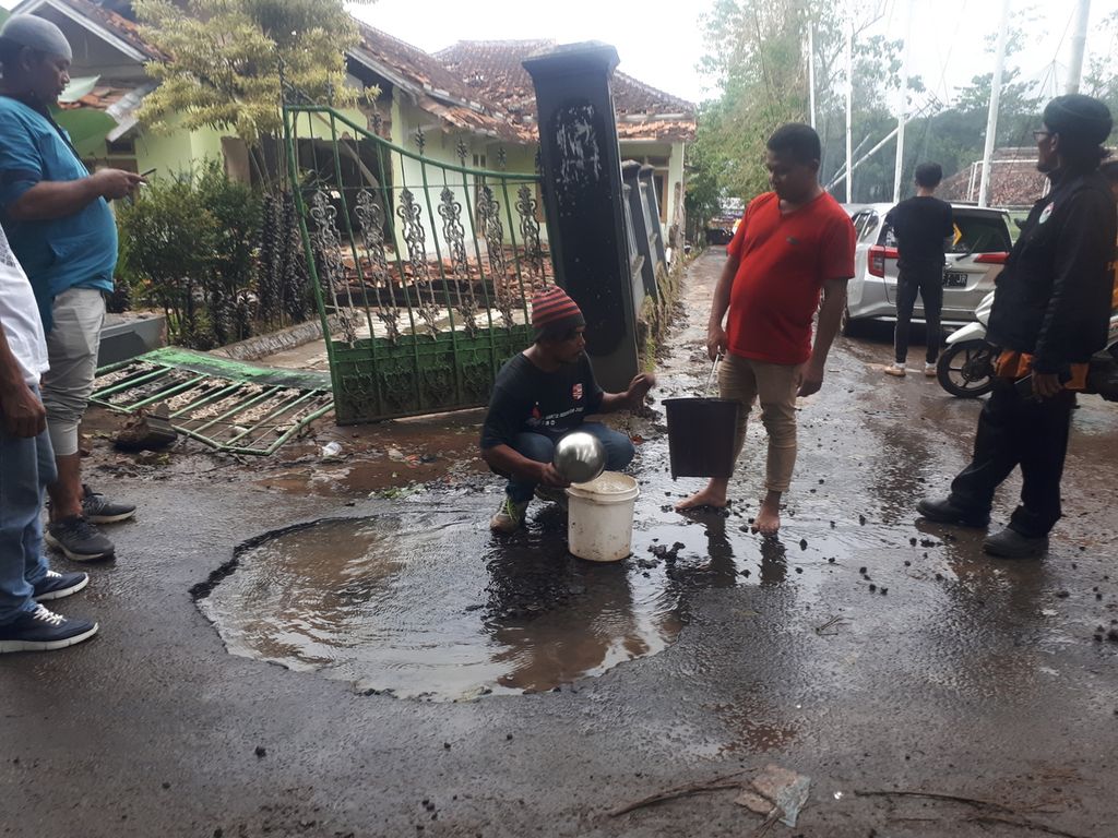 Ivan (37) mengambil air di kubangan aspal di Kampung Garogol, Cibulakan, Cugenang, Cianjur, Jawa Barat, Sabtu (26/11/2022).