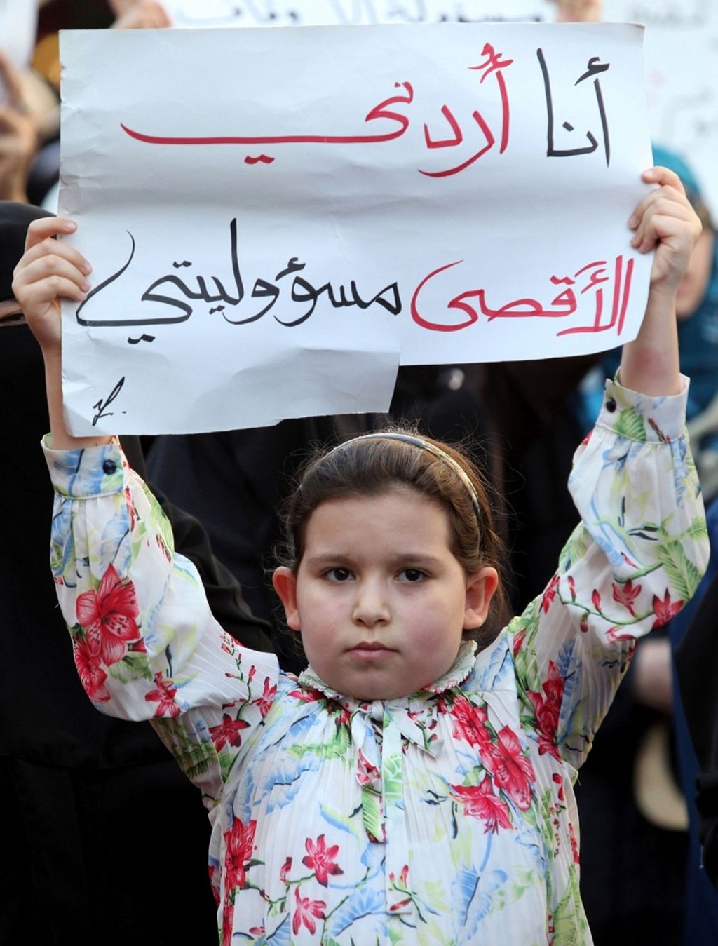 Seorang anak perempuan mengangkat poster bertuliskan pesan dalam bahasa Arab, yang berarti "Aku orang Jordania, Al-Aqsa adalah tanggung jawabku", dalam unjuk rasa di Amman, Jordania, 15 Juli 2021. 
