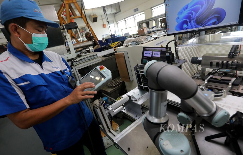 Teknisi dari PT Akebono Brake Astra Indonesia di kawasan Kelapa Gading, Jakarta Utara, memberikan perintah kepada robot dari sebuah papan modul layar sentuh yang terhubung dengan alat pendeteksi keretakan pada produk kampas rem, Rabu (1/2/2023).