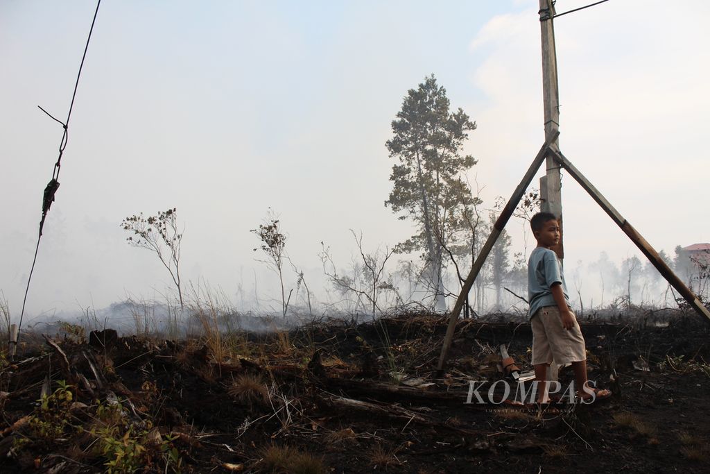 Seorang anak di Desa Tumbang Nusa, Kabupaten Pulang Pisau, Kalimantan Tengah, Jumat (22/9/2023) sore menunggui lahannya yang terbakar bersama keluarganya. Setidaknya lima hektar lahan gambut terbakar di sekitar desa tersebut.