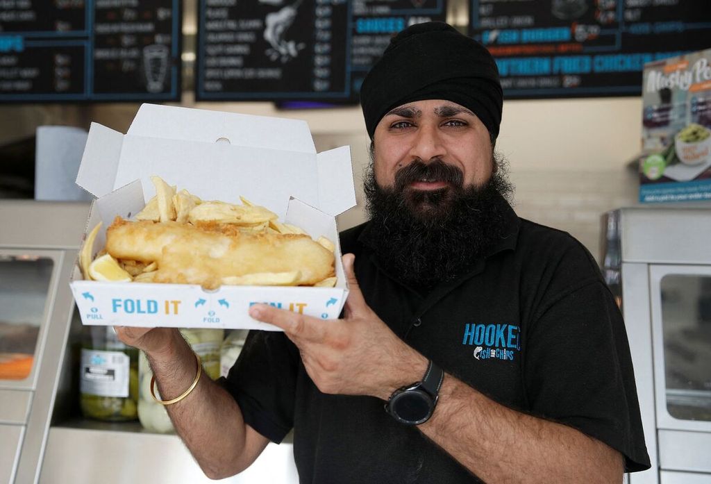 Pemilik Hooked Fish and Chips, Bally Singh, menunjukkan seporsi makanan itu pada Rabu (25/5/2022), di  West Drayton, Inggris.  Harga ikan untuk bahan baku menu itu sudah naik 75 persen dibanding 2021. Sementara minyak biji matahari naik 60 persen dan tepung 40 persen. 