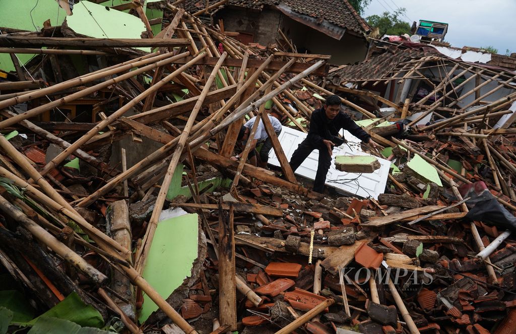 Warga Kampung Rawacina, Nagrak, Kecamatan Cianjur, Kabupaten Cianjur, Jawa Barat, mencari benda-benda yang bisa diselamatkan di antara timbunan runtuhan rumahnya akibat gempa, Rabu (23/11/2022).