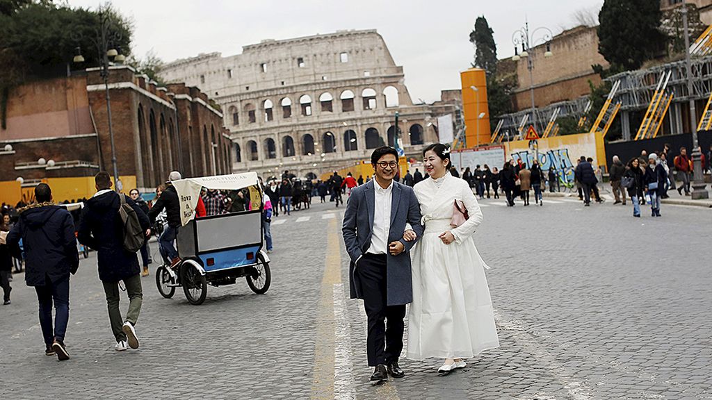 Sepasang pengantin  yang baru menikah, Sabtu (30/12), berjalan beriring di dekat Colosseum di Roma, Italia. Pemerintah Italia saat ini tengah bergulat dengan angka pengangguran yang tinggi.