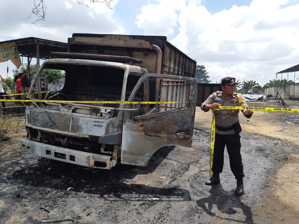 Petugas memasang garis polisi di lokasi gudang penampungan minyak ilegal yang terbakar di Jalan Lingkar Barat, Kota Jambi, Senin (15/8/2022). Kebakaran itu menunjukkan tambang minyak liar kembali marak di Jambi.