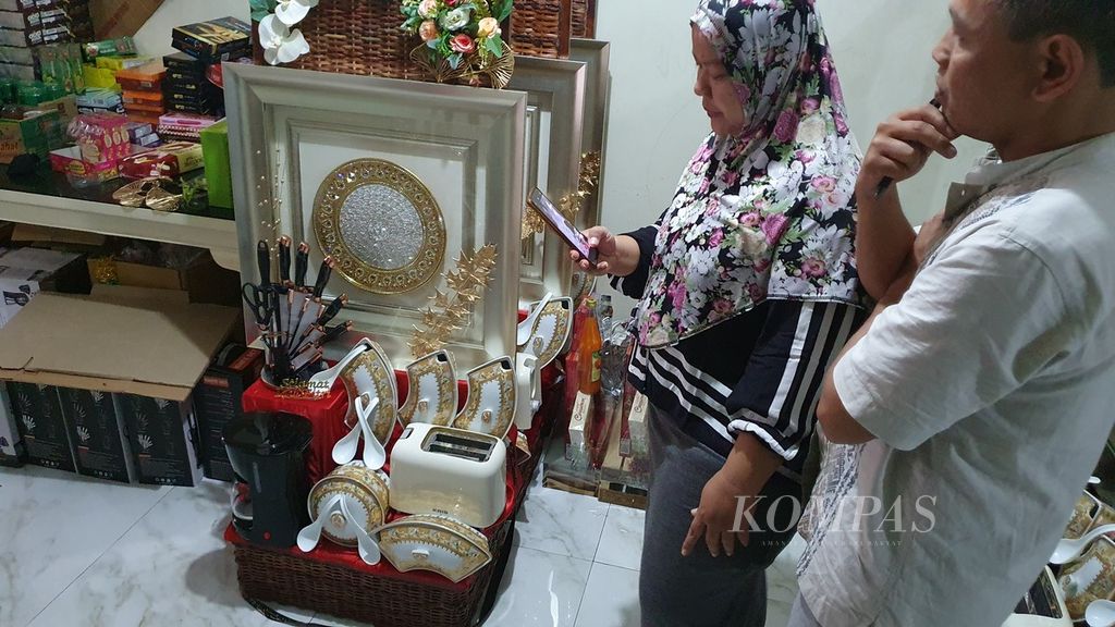 Ibu Dijah berkomunikasi dengan pelanggan di depan parsel pesanan berisi pecah belah yang baru selesai ia rangkai di Cikini, Jakarta Pusat, Selasa (26/3/2024).