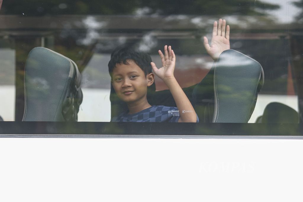Seorang anak melambaikan tangannya saat bus yang ditumpanginya meninggalkan Terminal Kampung Rambutan, Jakarta, Sabtu (23/12/2023). 