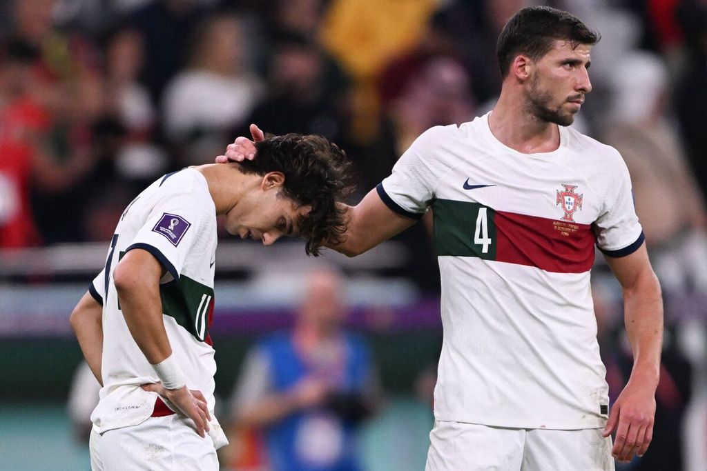 Pemain Portugal Joao Felix, kiri, dihibur Ruben Dias setelah dikalahkan Maroko di babak perempat final Piala Dunia Qatar 2022, Sabtu (10/12/2022) di Al-Thumama Stadium di Doha.