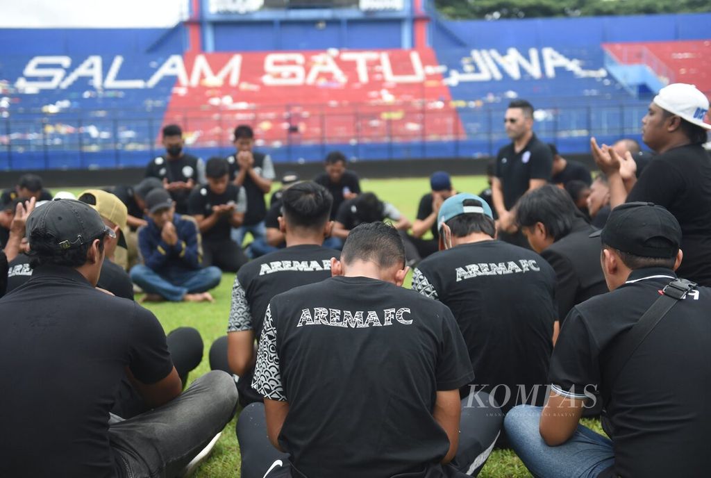 Pemain dan ofisial Arema FC berada di tengah lapangan di Stadion Kanjuruhan untuk memberikan penghormatan bagi korban yang meninggal saat kerusuhan, di Kabupaten Malang, Jawa Timur, Senin (3/10/2022).  