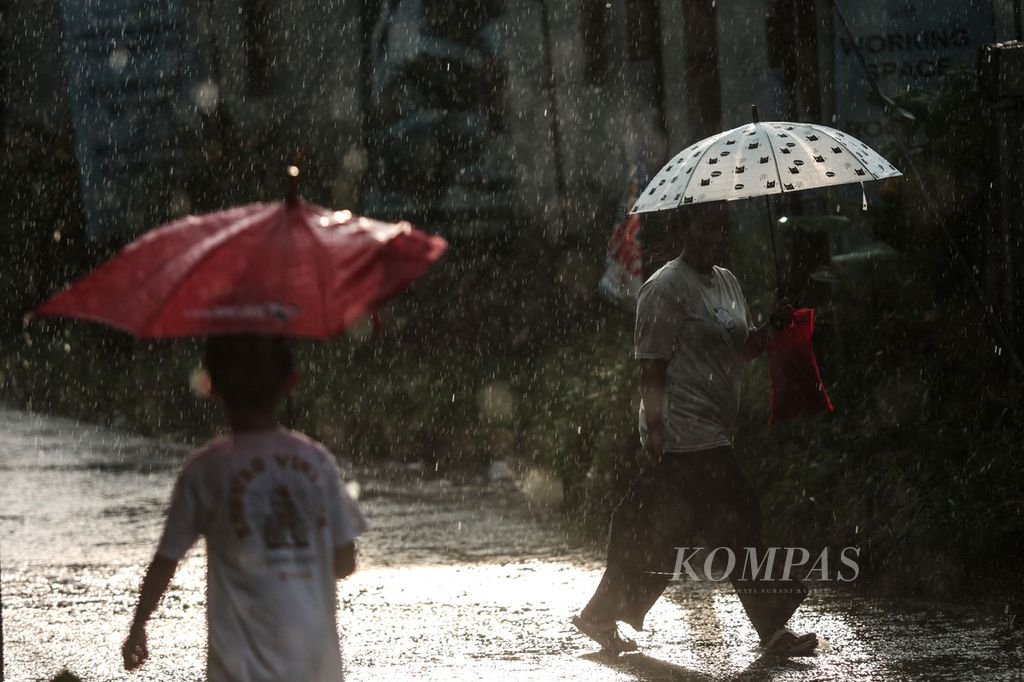 Warga menggunakan payung saat hujan deras mengguyur kawasan Pondok Cabe, Tangerang Selatan, Banten, Senin (8/5/2023). Perubahan cuaca dari panas ke hujan patut diwaspadai saat musim pancaroba seperti saat ini.