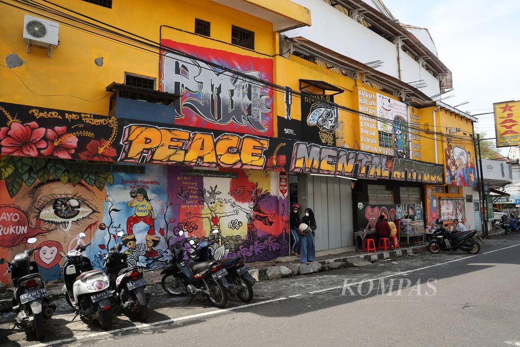 Warga beraktivitas di depan mural bertema "Ayo Rukun" di Jalan Pajajaran, Kota Magelang, Jawa Tengah, Senin (23/5/2022). 