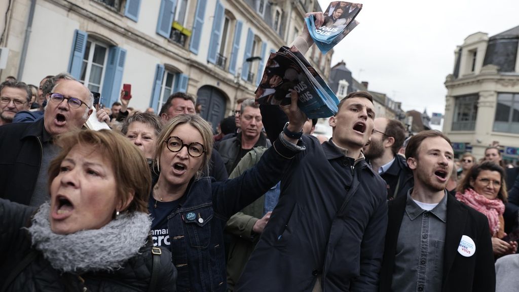 Pendukung petahana Presiden Perancis Emmanuel Macron berteriak saat pemimpin sayap kanan Perancis Marine Le Pen tiba di Saint-Pierre-en-Auge, Normandia, untuk berkampanye, Senin (18/4/2022). 