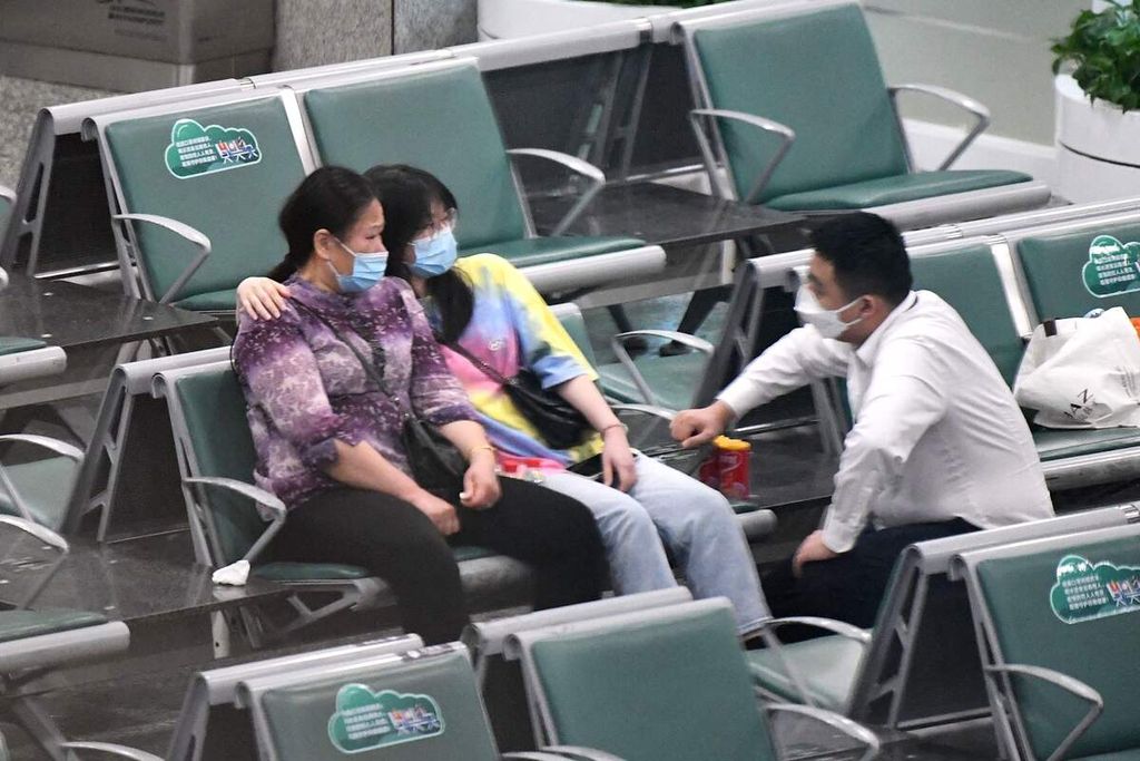 Keluarga dari penumpang pesawat China Eastern MU5735 duduk menunggu informasi di Bandara Internasional Guangzhou Baiyun, Senin (21/3/2022).  