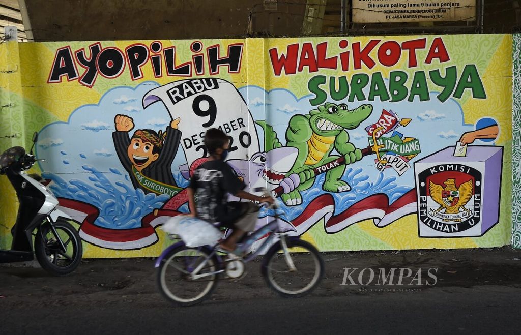 Warga melewati jalan yang terdapat mural pemilihan wali kota yang dibuat peserta lomba mural yang diselenggarakan KPU Kota Surabaya di Kecamatan Jambangan, Surabaya, Jawa Timur, Minggu (4/10/2020). 