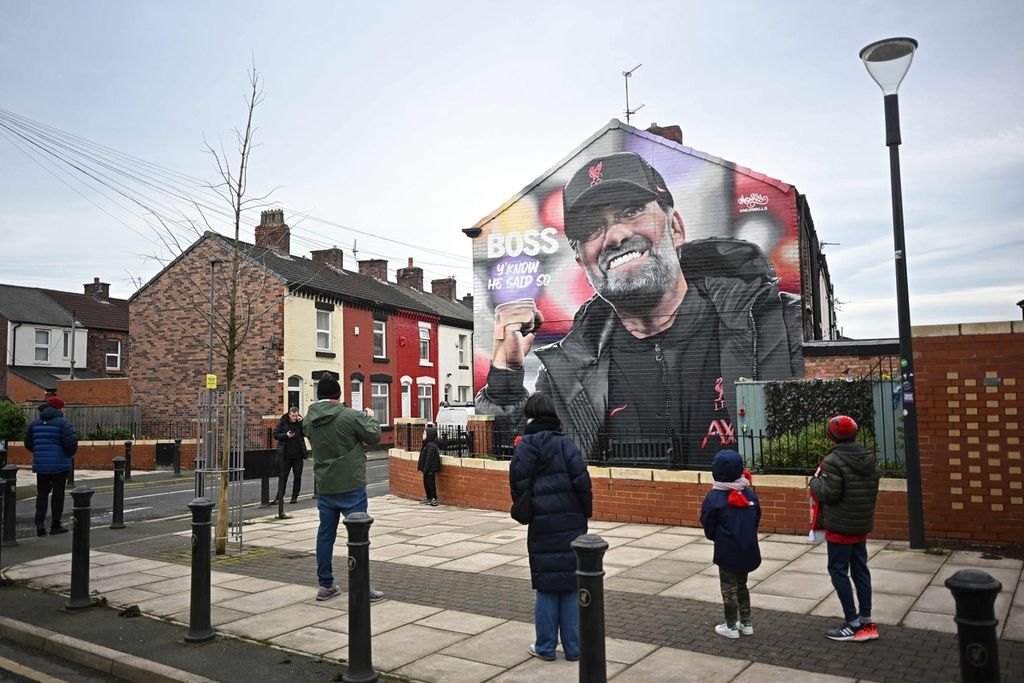 Pejalan kaki melewati mural wajah Manajer Liverpool Juergen Klopp karya seniman Hugh Whitaker, tak jauh dari lokasi pertandingan babak keempat Piala FA antara Liverpool dan Norwich City di Stadion Anfield, Liverpool, Minggu (28/1/2024). Klopp akan meninggalkan Liverpool pada akhir musim ini.