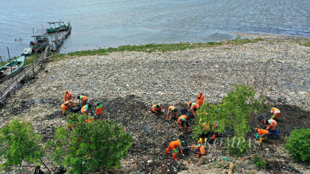 Petugas Suku Dinas Lingkungan Hidup Kabupaten Administrasi Kepulauan Seribu membersihkan sampah laut di muara Kanal Timur di Marunda Kepu, Cilincing, Jakarta Utara, Selasa (10/1/2023). 
