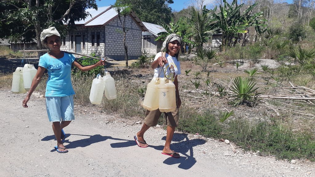 Warga berjalan kaki memikul air bersih yang diambil dari kali di Desa Oenoni, Kecamatan Amarasi Timur, Kabupaten Kupang, Nusa Tenggara Timur, Minggu (22/8/2021). Hampir semua wilayah dilanda kekeringan ekstrem.
