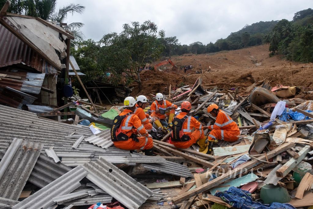 Sejumlah personel Badan SAR Nasional anggota Satuan Tugas Tanggap Bencana Natuna beristirahat di atas reruntuhan rumah warga yang terkena bencana tanah longsor di Desa Pangkalan, Pulau Serasan, Natuna, Kepulauan Riau, Sabtu (11/3/2023).