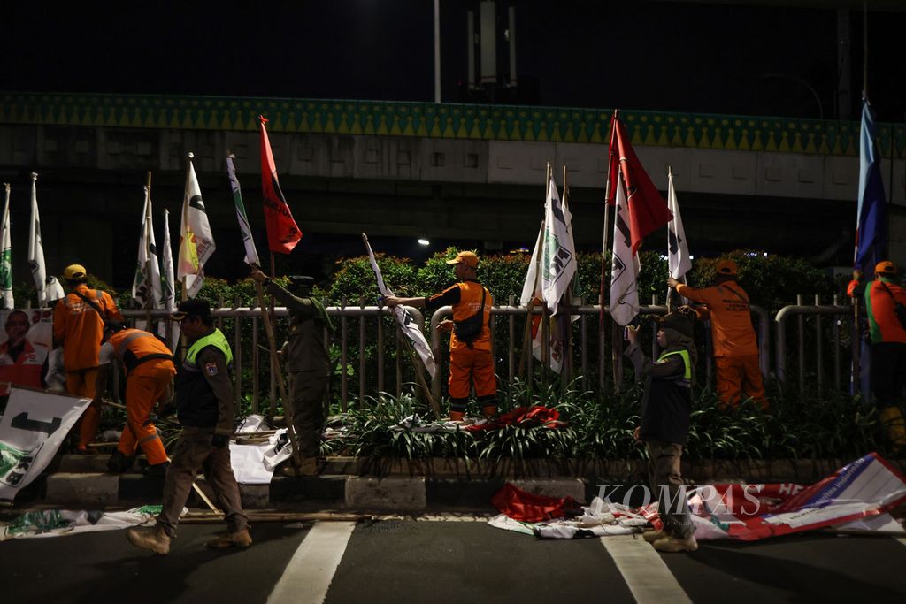 Petugas Satpol PP dan PPSU menertibkan bendera peserta Pemilu 2024 di Jalan Kapten Tendean, Jakarta, Minggu (11/2/2024).
