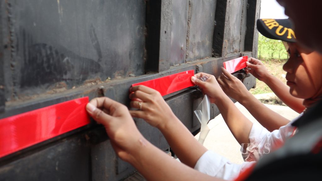 Petugas memasang stiker reflektif pada sebuah truk di Rest Area Kilometer 130 ruas Tol Cikopo-Palimanan, Kabupaten Indramayu, Jawa Barat, Jumat (10/3/2023). Stiker itu dapat membantu pencahayaan saat malam hari sehingga mencegah potensi kecelakaan tabrak belakang.
