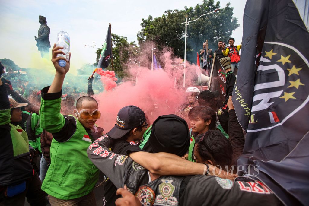 Para pengemudi ojek daring menyalakan suar saat berunjuk rasa di kawasan Patung Kuda Wijaya, Jakarta, Kamis (29/8/2024). 