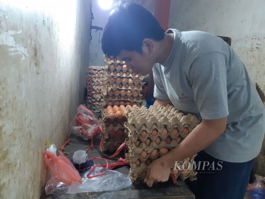 Pedagang mengikat telur ayam pesanan warga di kiosnya di Blok III Pasar Raya Padang, Padang, Sumatera Barat, Kamis (8/12/2022). 