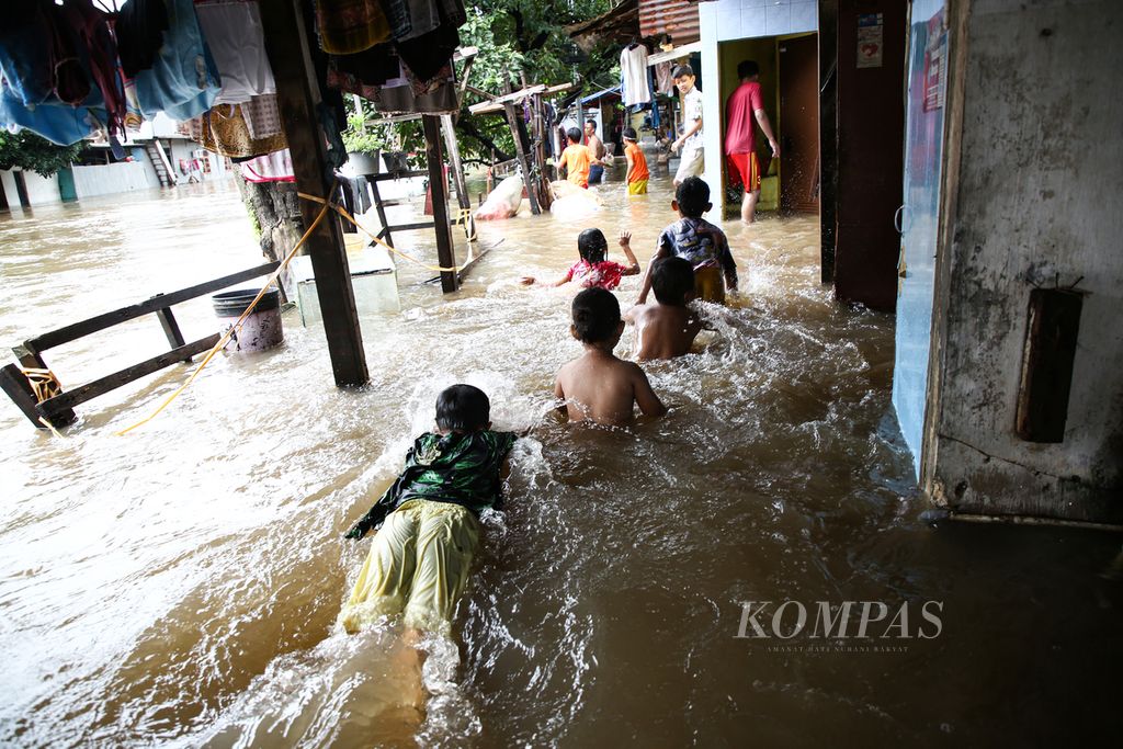 Anak-anak bermain air banjir yang merendam hunian di bantaran Kali Krukut di Kelurahan Karet Tengsin, Tanah Abang, Jakarta Pusat, Selasa (25/2/2020). Banjir akibat curah hujan yang tinggi ini tidak hanya merendam kawasan permukiman, tetapi juga memutus akses di sejumlah wilayah di Jakarta, Bekasi, dan Tangerang. 