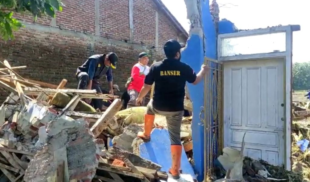 Warga Desa Kutamendala, Kecamatan Tonjong, Kabupaten Brebes, Jateng, berada di atas puing-puing rumah yang rusak tersapu banjir bandang, Kamis (17/3/2022). Banjir itu membuat sedikitnya 10 rumah rusak, enam di antaranya roboh tersapu air. 