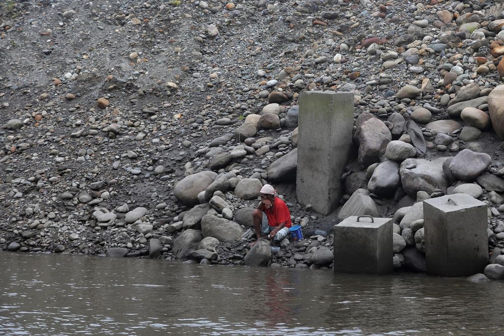 Kamoro tribesmen fish under an embankment built by a mining company to separate the tailings waste stream.