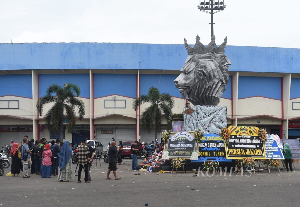 Warga mengunjungi Patung Singa "Tegar" di depan Stadion Kanjuruhan, Kabupaten Malang, Jawa Timur, Senin (3/10/2022), untuk berdoa bagi korban yang meninggal saat kerusuhan, akhir pekan lalu. Tragedi Kanjuruhan perlu menjadi momentum untuk memperbaiki standar keselamatan stadion di Indonesia.